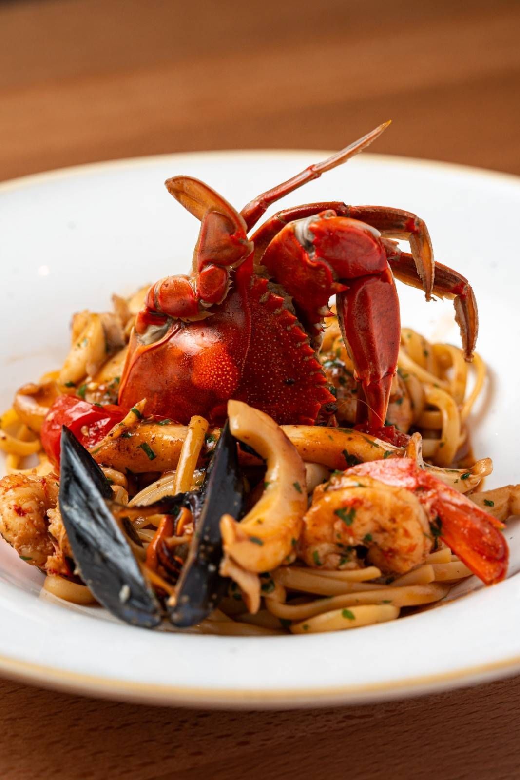 Pasta con mariscos: langosta, mejillones, gambas y calamares en un bol blanco.