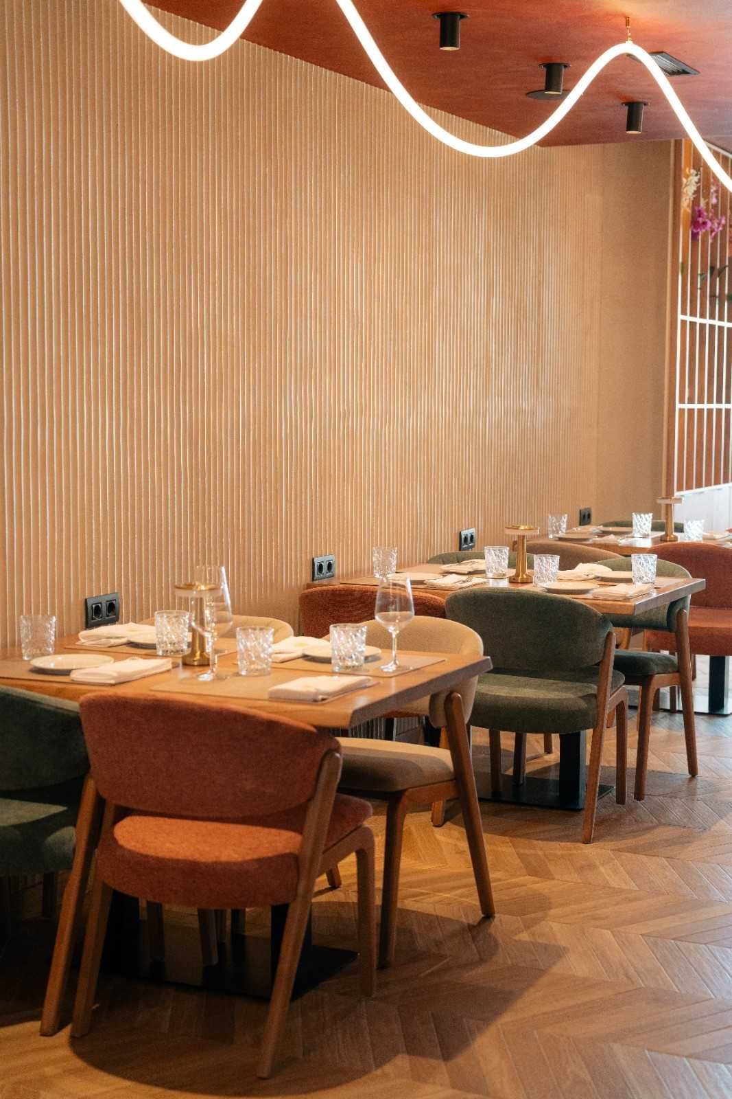Acogedor comedor de restaurante con mesas de madera, sillas tapizadas y una cálida iluminación ambiental.