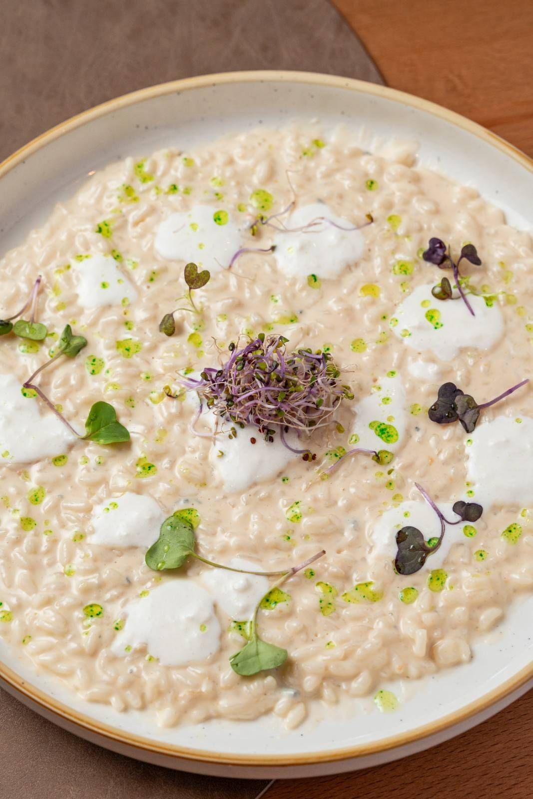 Risotto cremoso con hierbas y flores comestibles sobre un plato blanco.