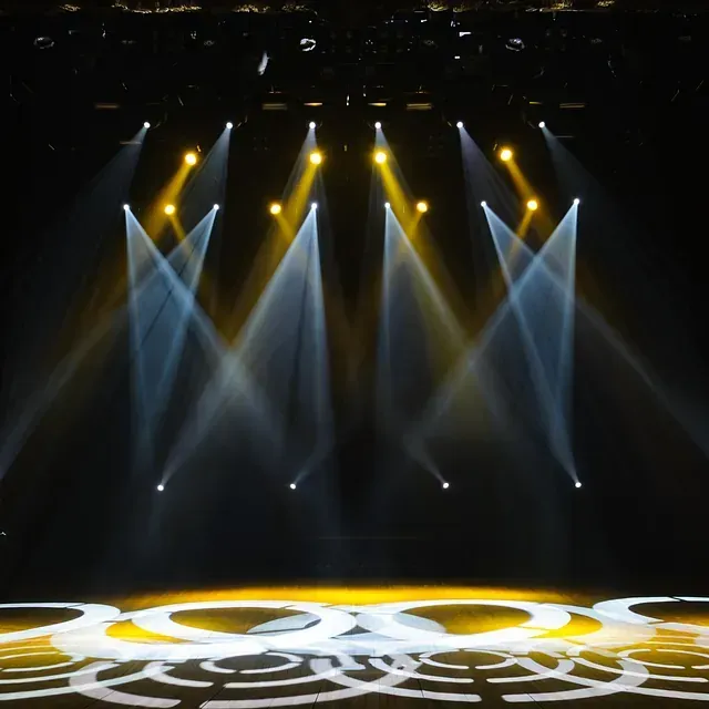 Escenario con focos que proyectan rayos amarillos y azules sobre el suelo, donde se proyecta un patrón.