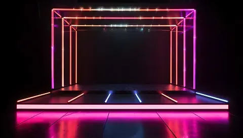Escenario iluminado con neón, con un marco de caja de luces rosas y naranjas, sobre un suelo reflectante y contra un fondo oscuro.