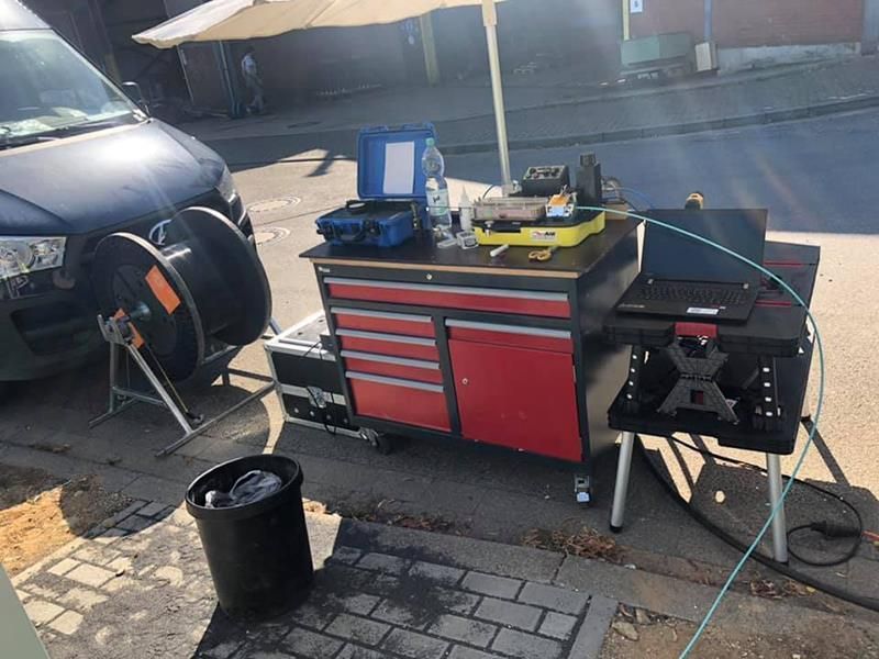 Neben einer Werkbank, auf der ein Laptop liegt, parkt ein Lieferwagen.