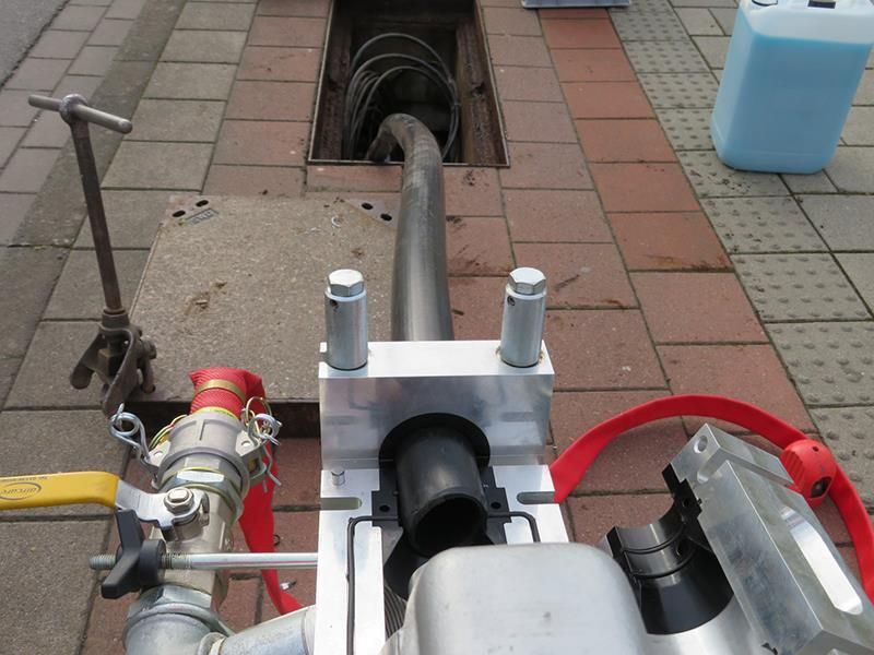 Ein Schlauch ist an eine Maschine auf dem Bürgersteig angeschlossen