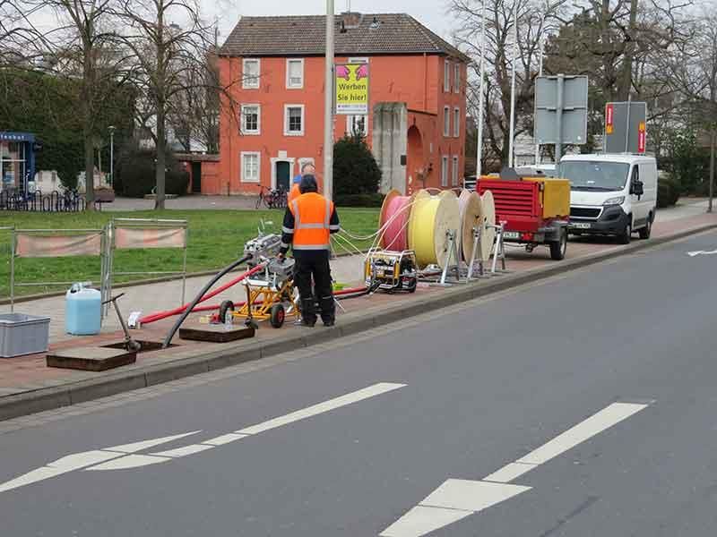Ein Mann in einer orangefarbenen Weste steht am Straßenrand.