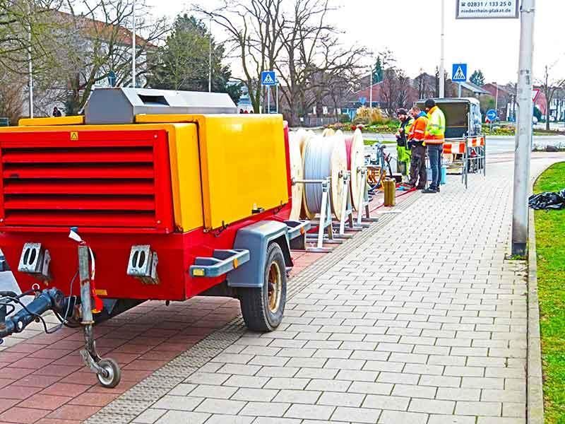Ein rot-gelber Anhänger steht auf einem Gehweg.