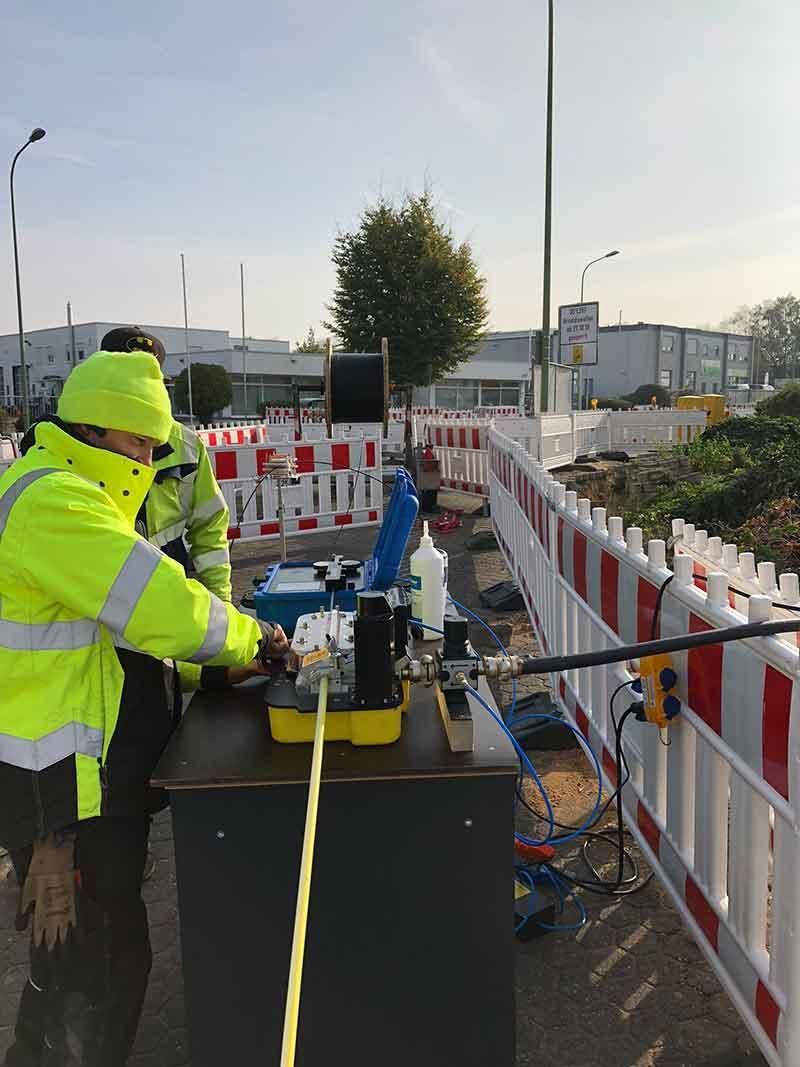 Ein Mann in einer neongelben Jacke arbeitet an einer Maschine.