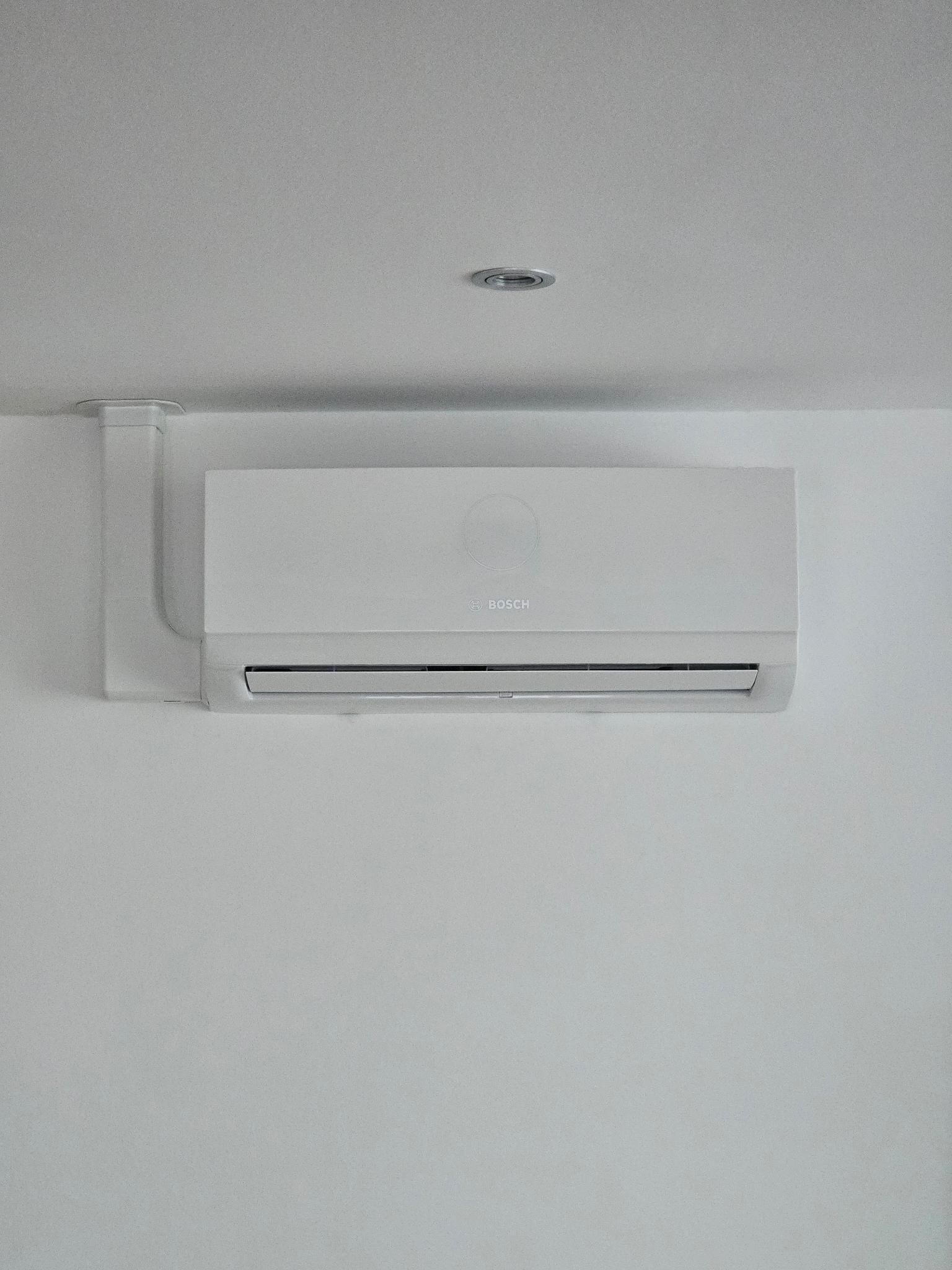 Weiße, an der Decke montierte Klimaanlage in einem schlichten Raum.