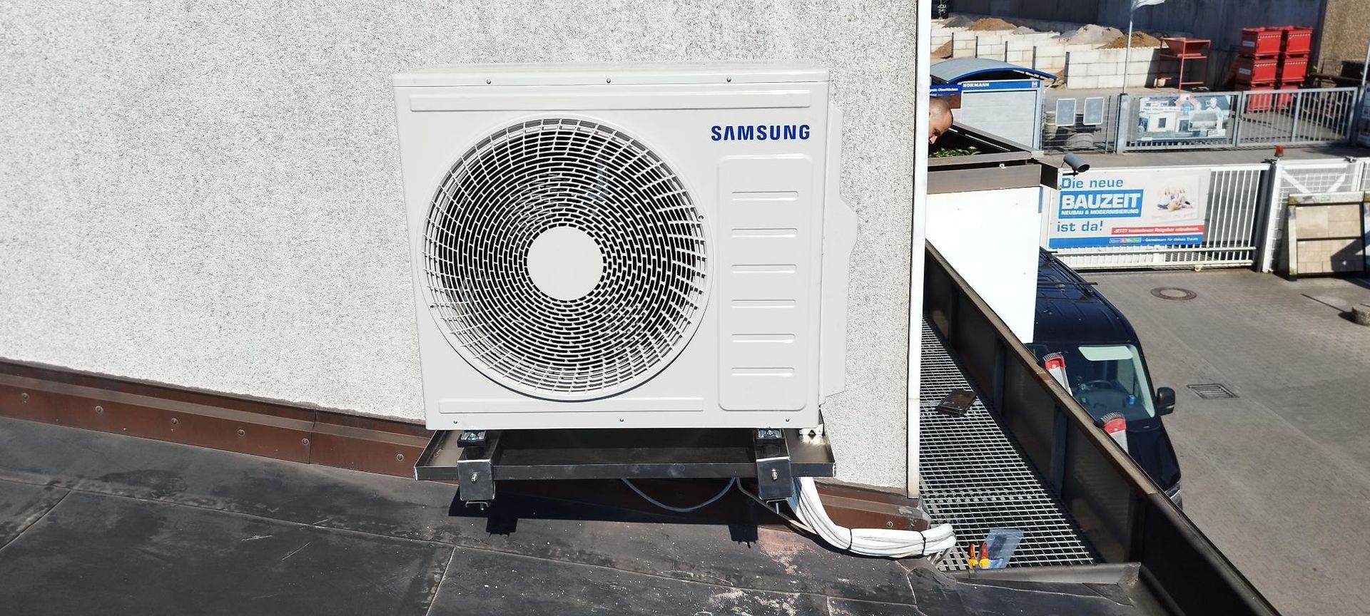 Außenklimaanlage an der Wand neben einem Ladebereich mit Paletten und Ausrüstung montiert.