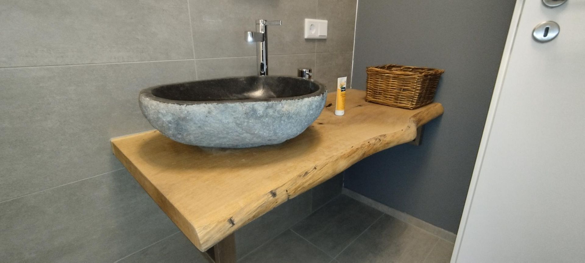 Ein graues Steinwaschbecken auf einer Holzarbeitsplatte in einem modernen Badezimmer