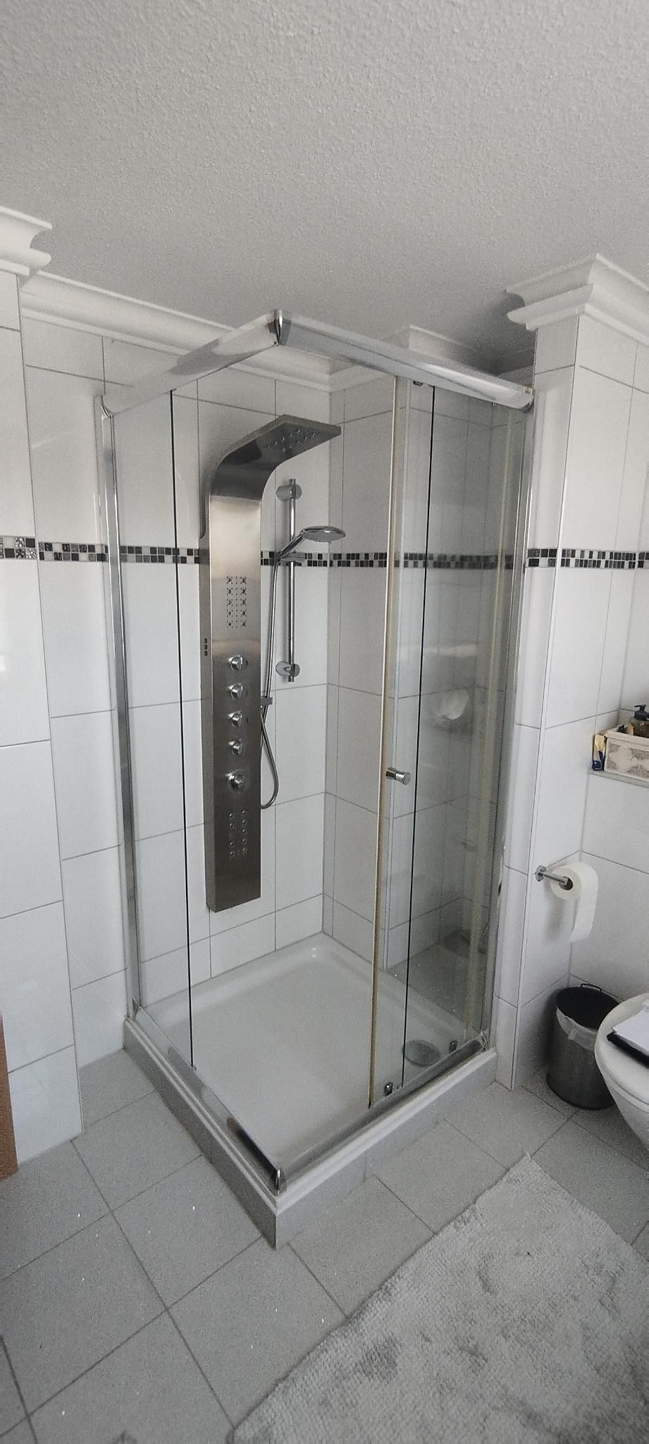 Begehbare Dusche mit Glasabtrennung und Chromarmaturen in einem gefliesten Badezimmer