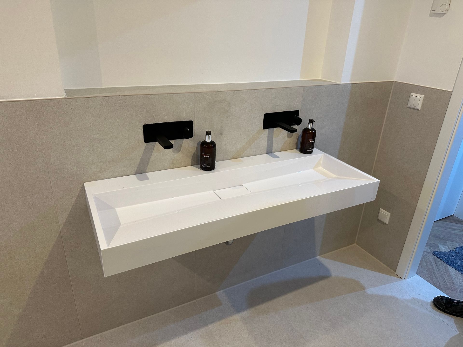 Modernes, wandmontiertes Doppelwaschbecken mit schwarzen Armaturen in einem minimalistischen Badezimmer