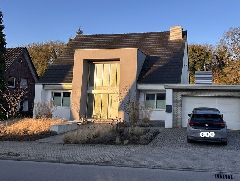 Modernes Haus mit hohem Mitteleingang, Auffahrt und davor geparktem schwarzen SUV.