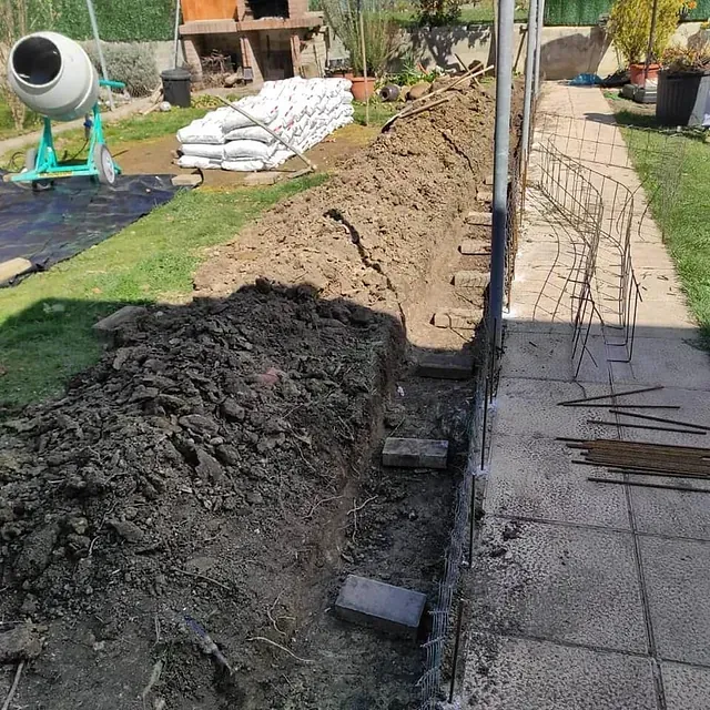 Un gran montón de tierra se encuentra junto a una hormigonera.
