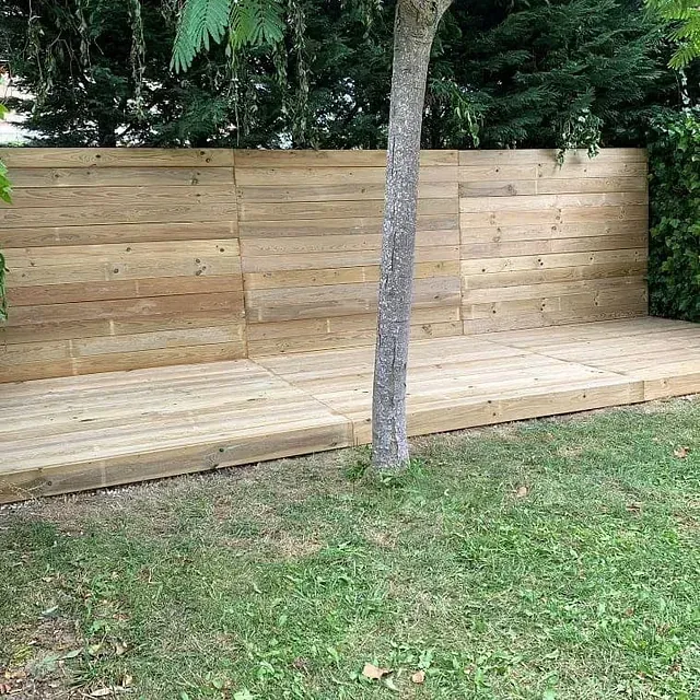 Un banco de madera está sentado en el césped al lado de un árbol.