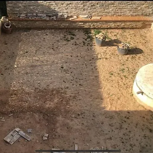 Una vista aérea de un campo de tierra con una pared de ladrillos al fondo.