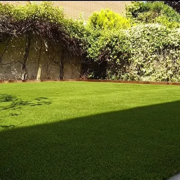 Un gran césped verde exuberante con una valla al fondo.