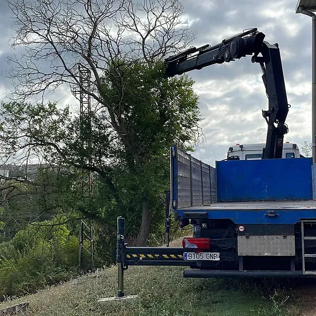 Un camión azul con una grúa en la parte trasera está estacionado en un campo