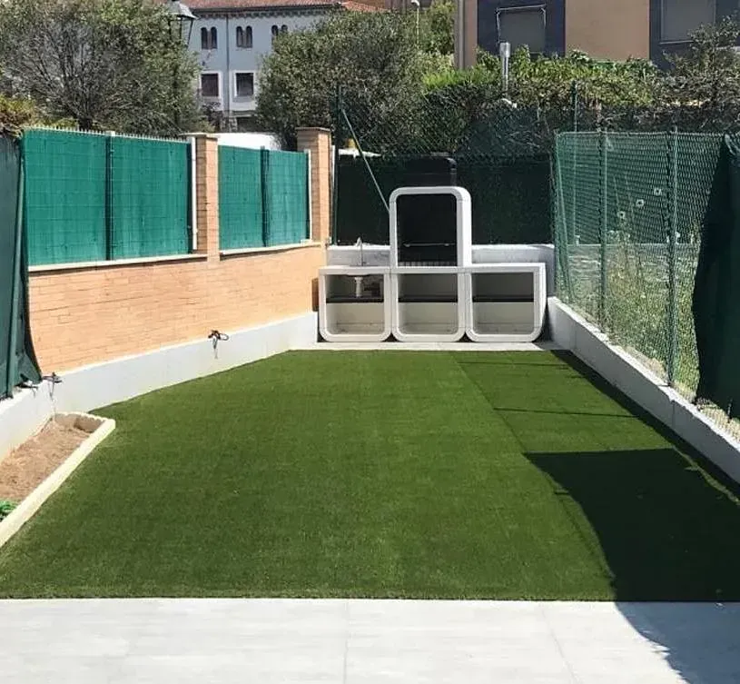 Una valla verde rodea un exuberante césped verde.
