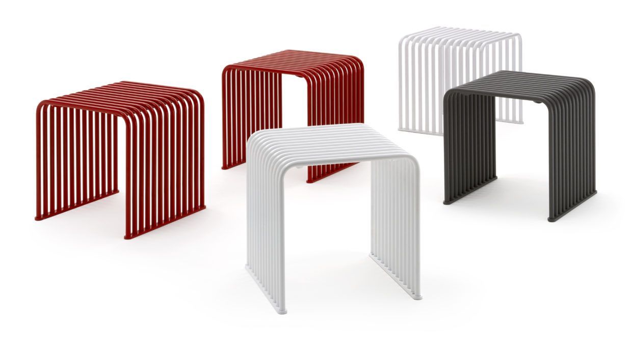 Un taburete rojo, blanco y negro están sentados uno al lado del otro sobre un fondo blanco.