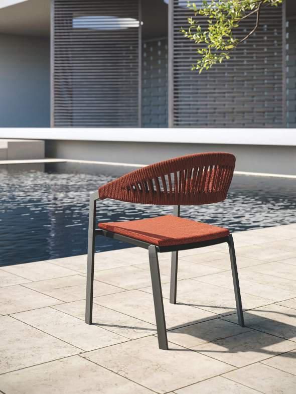 Una silla está sentada en un patio al lado de una piscina.