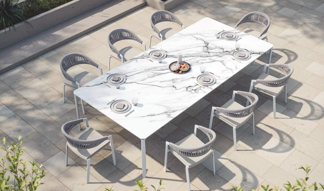 Una gran mesa blanca con sillas alrededor en un patio.