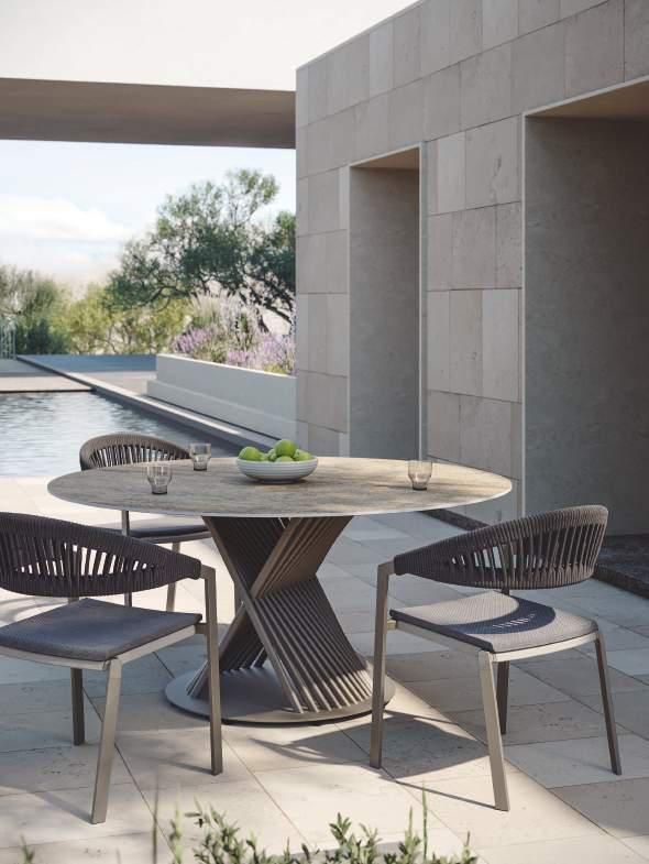 Una mesa y sillas están sentadas en un patio al lado de una piscina.