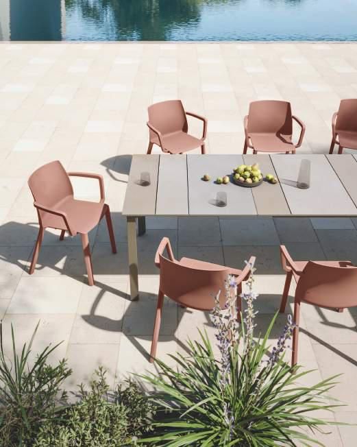 Una mesa con sillas alrededor y un bol de fruta encima.