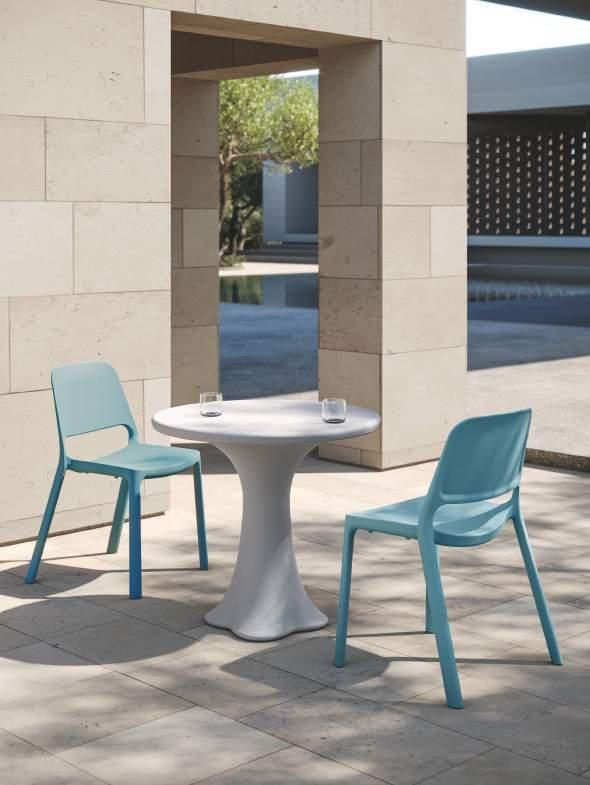 Una mesa blanca con dos sillas azules frente a una pared de ladrillos.