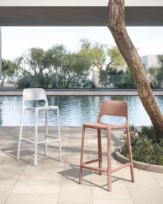 Dos taburetes de bar están uno al lado del otro cerca de una piscina.