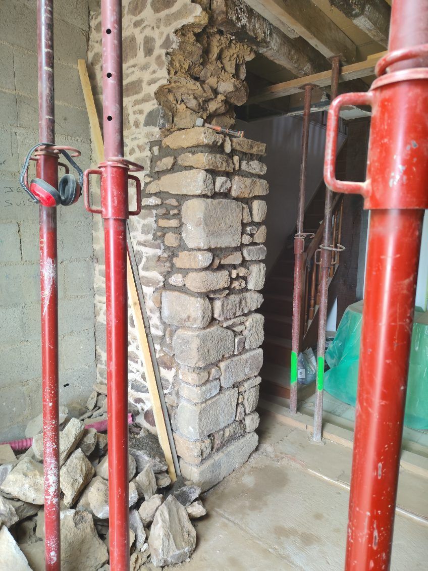 Pilier en pierre en construction avec échafaudages rouges et outils sur un chantier de rénovation