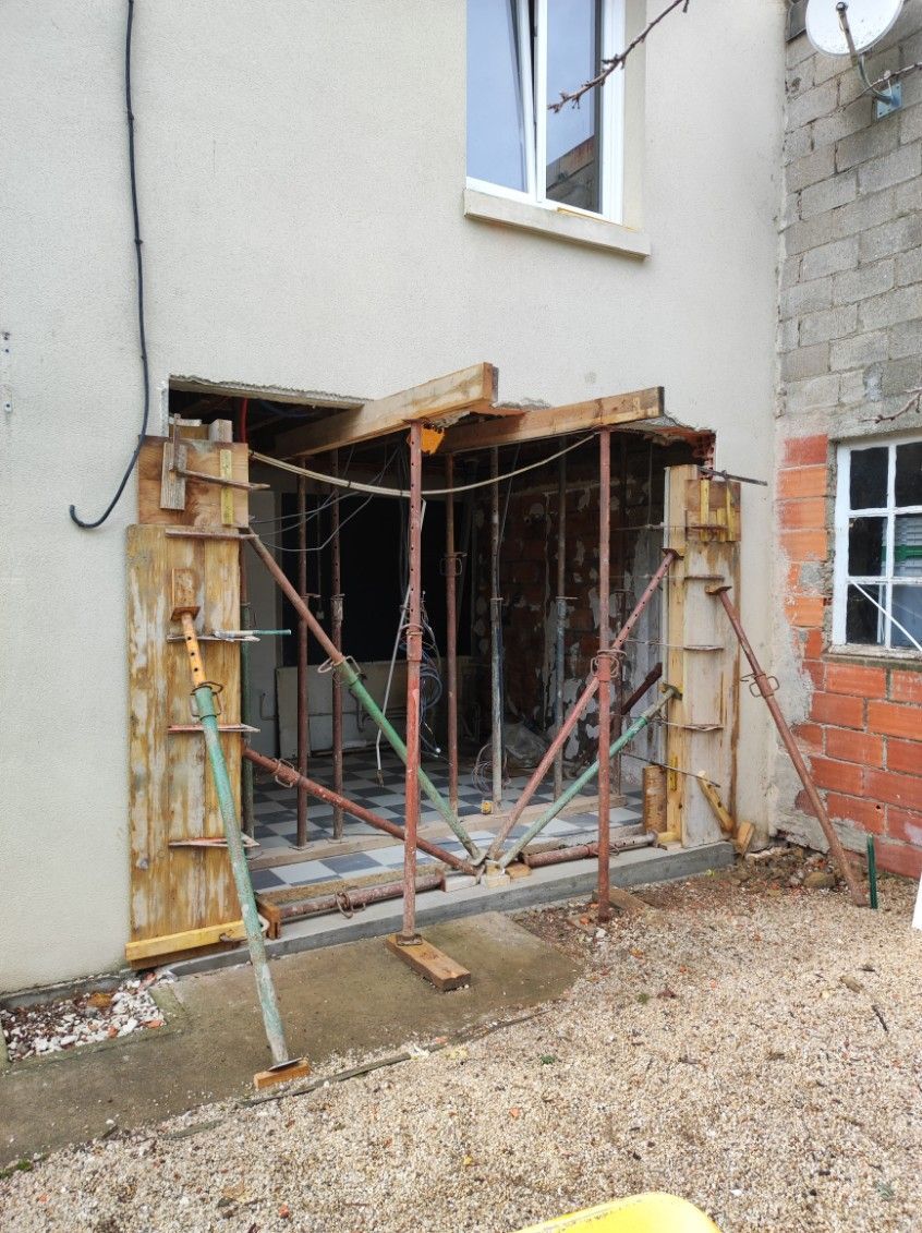Extérieur de la maison avec porte d'entrée en échafaudage et matériaux de construction dans une cour en gravier