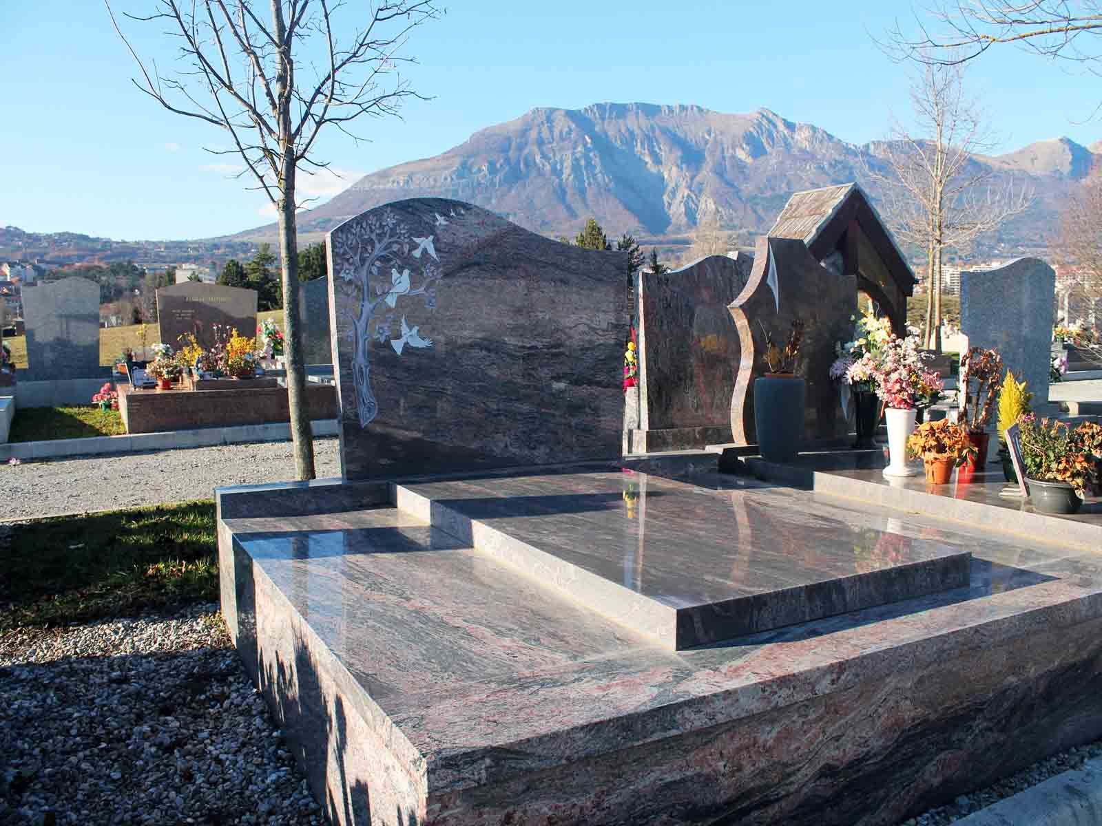 Pierre tombale en granit dans un cimetière avec des montagnes en arrière-plan.