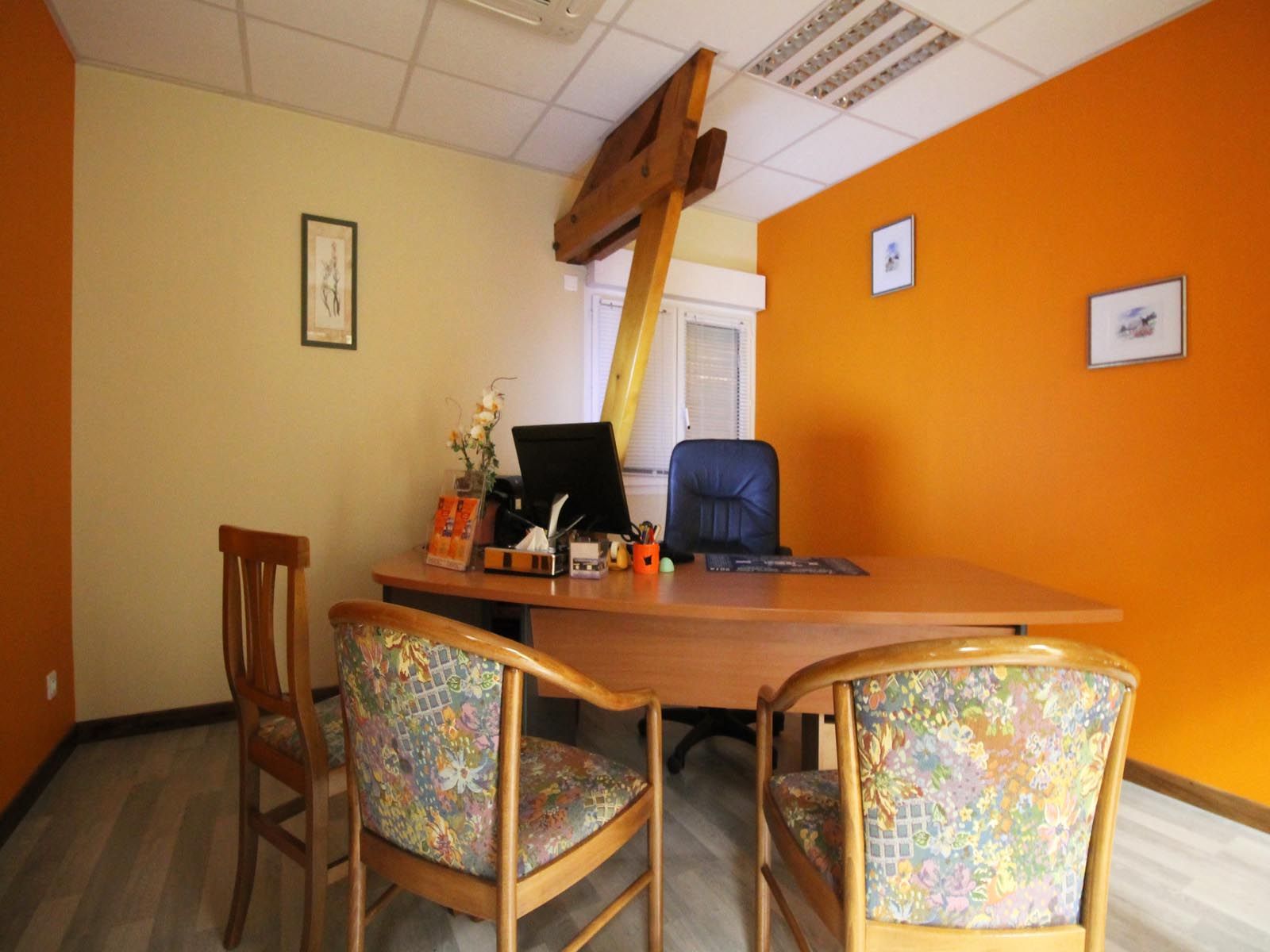 Bureau avec bureau, chaises, ordinateur et murs orange et beige.