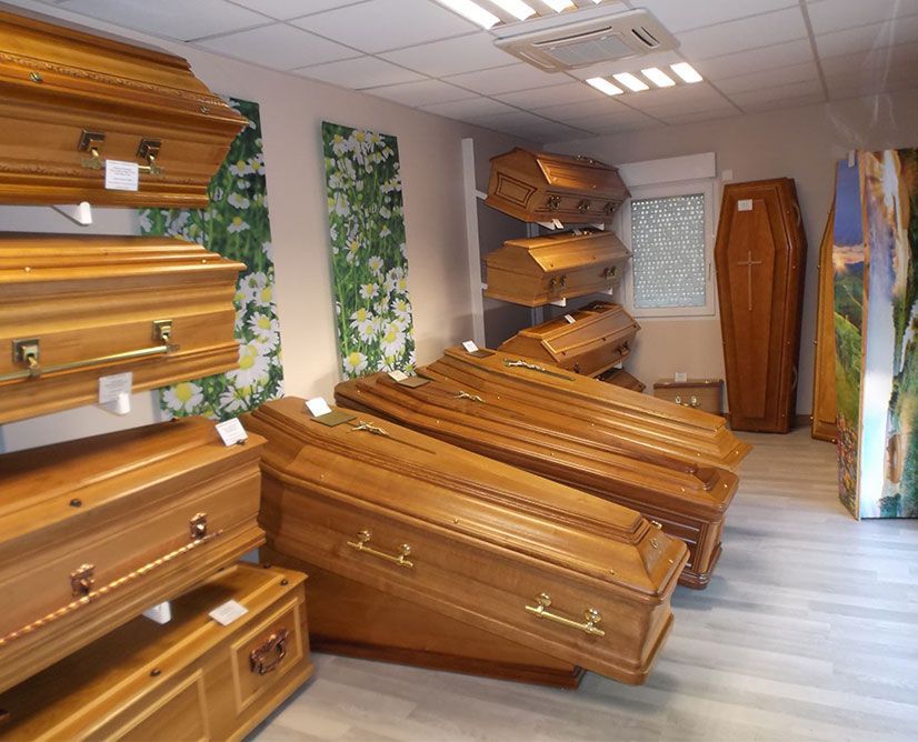 Une salle d'exposition présentant plusieurs cercueils en bois ; certains sont empilés, d'autres debout.