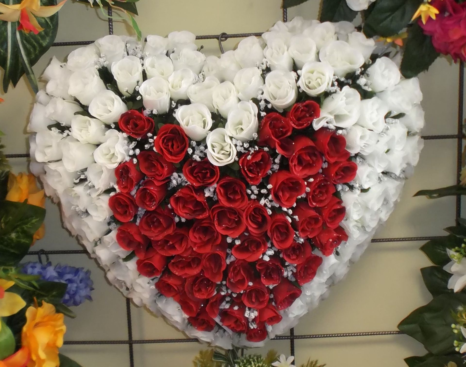 Composition florale en forme de cœur, composée de roses blanches et rouges, probablement pour un hommage ou une célébration.