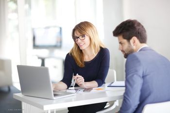 Zwei Personen vor Laptop an Tisch