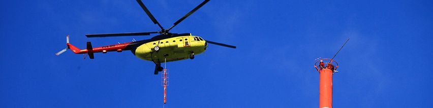 Ein gelb-roter Hubschrauber fliegt über einem roten Turm.