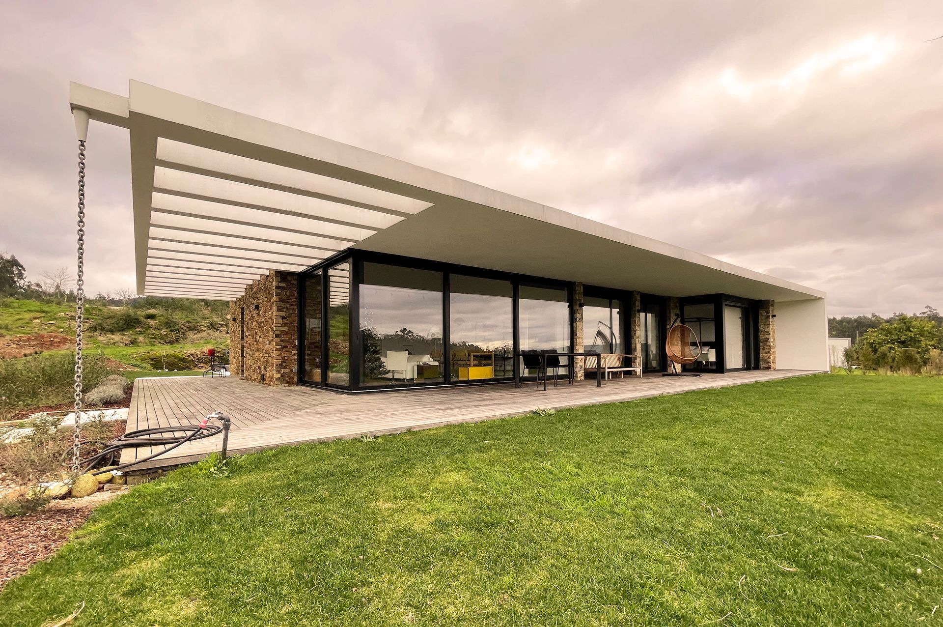 Una casa moderna con muchas ventanas y un gran jardín delante de ella.