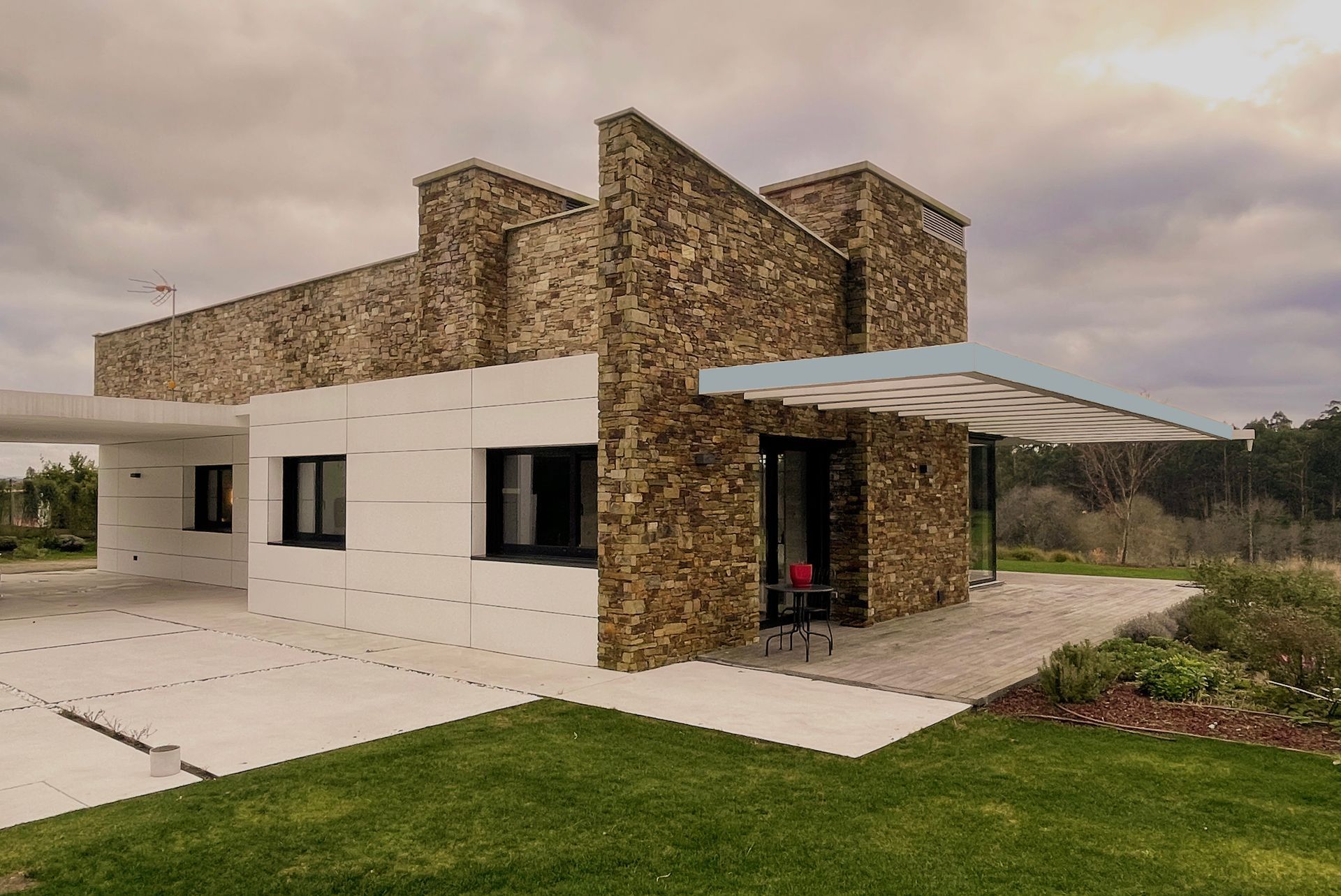 Una casa moderna con fachada de piedra y césped delante.