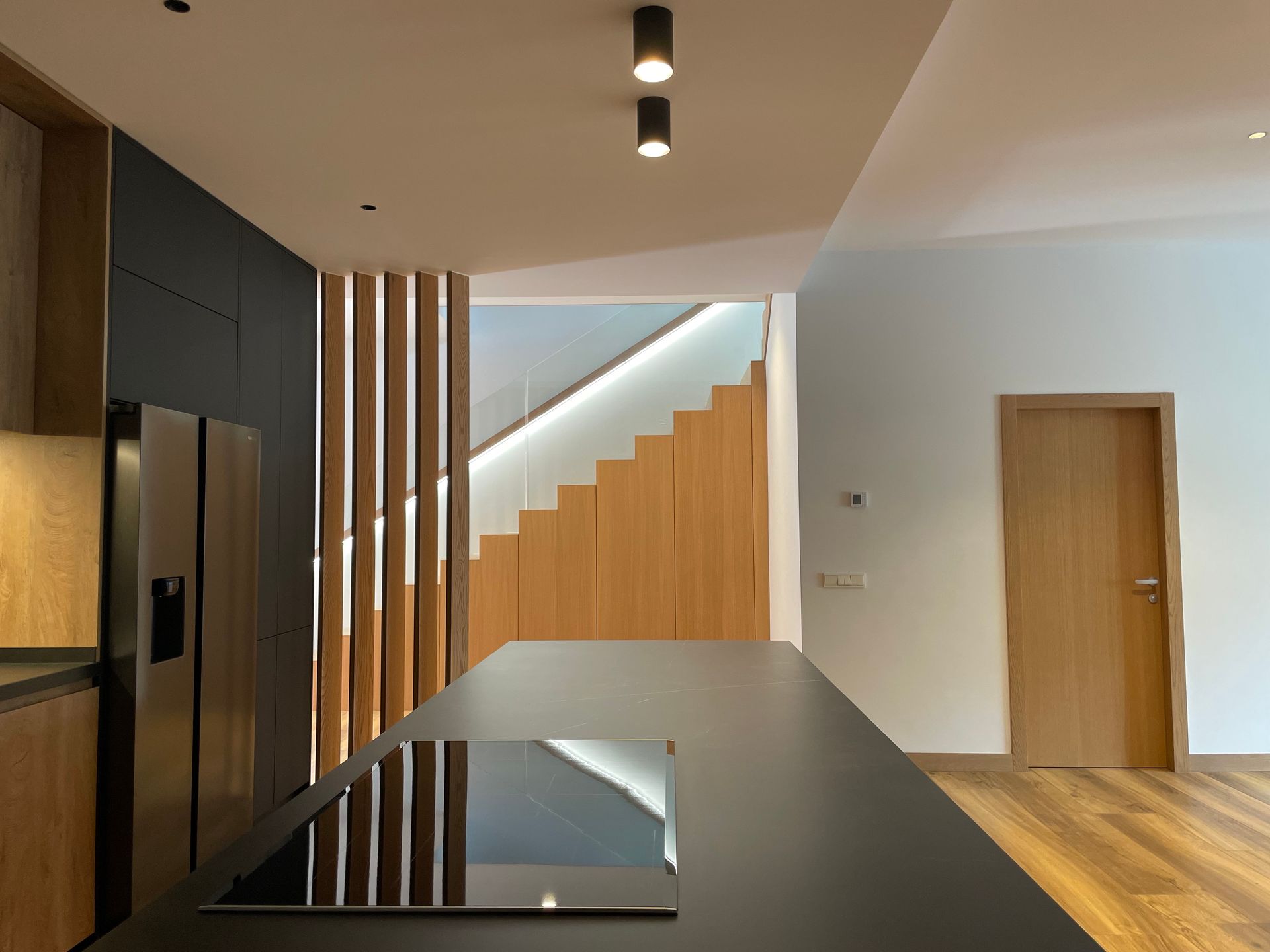 Una cocina con una gran isla y una escalera al fondo.