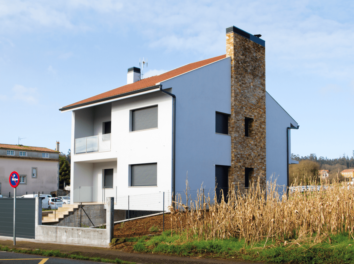 Una casa blanca con techo rojo y chimenea de piedra