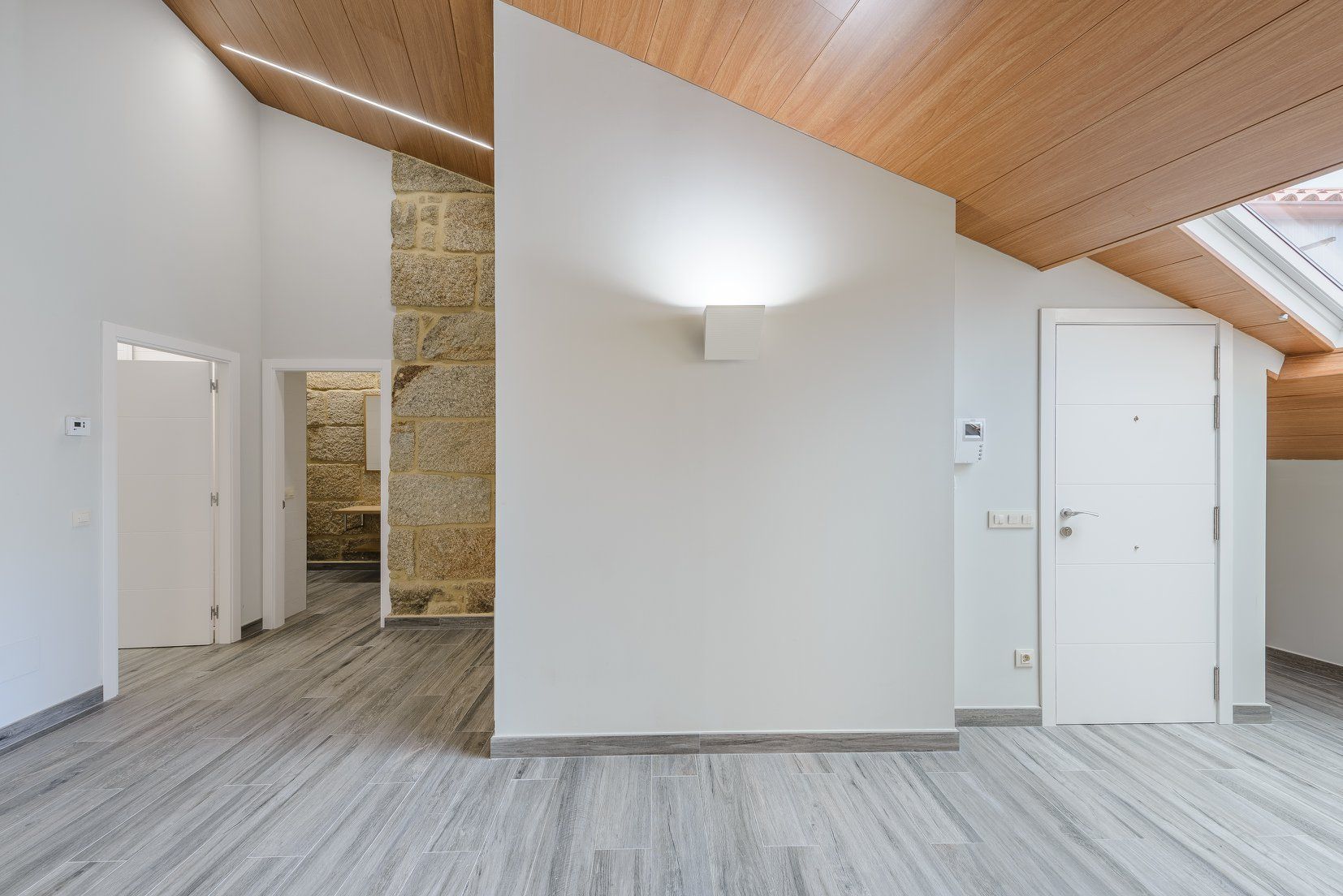 Una habitación vacía con techo de madera y paredes blancas.