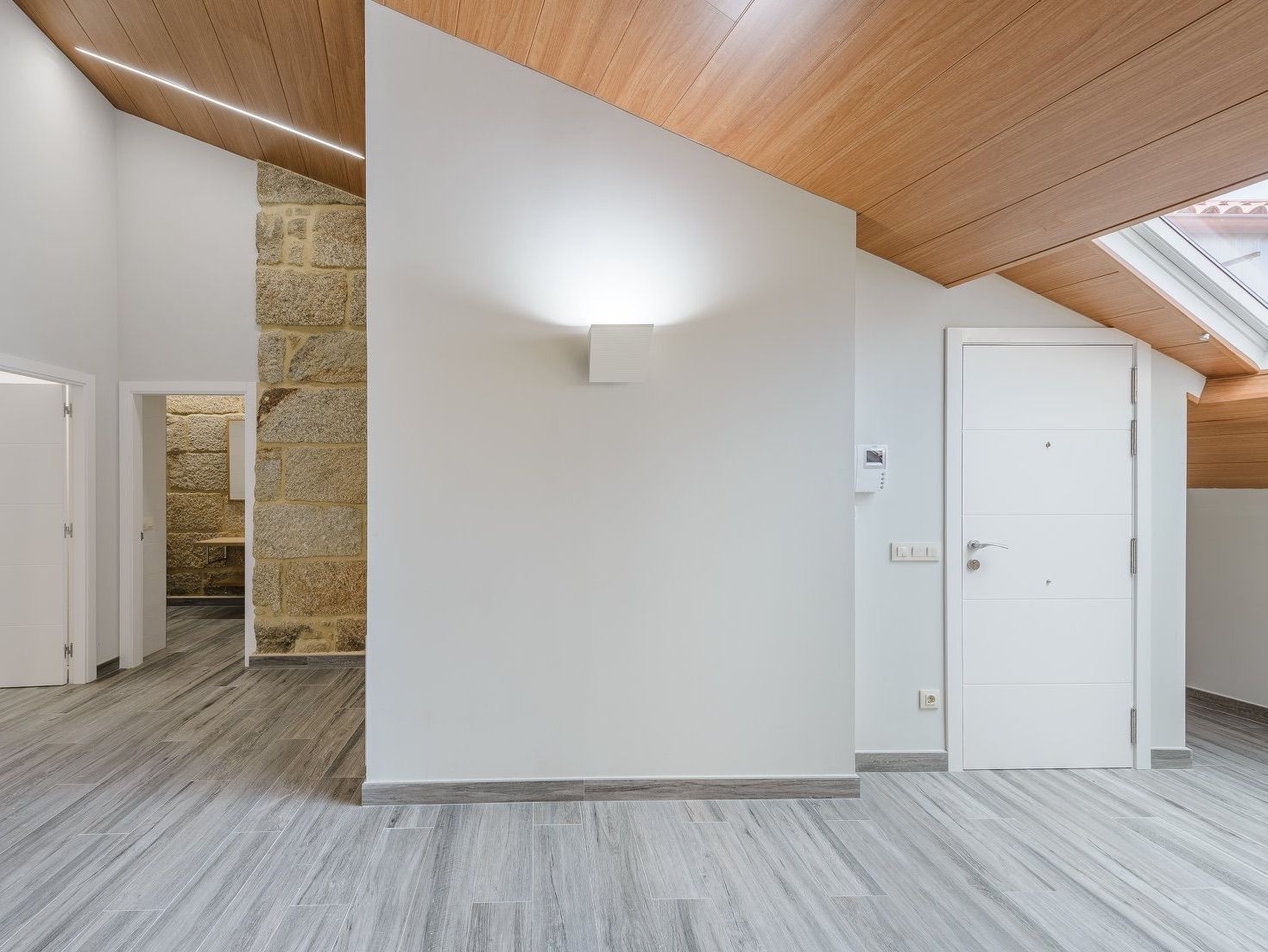 Una habitación vacía con paredes blancas y un techo de madera.