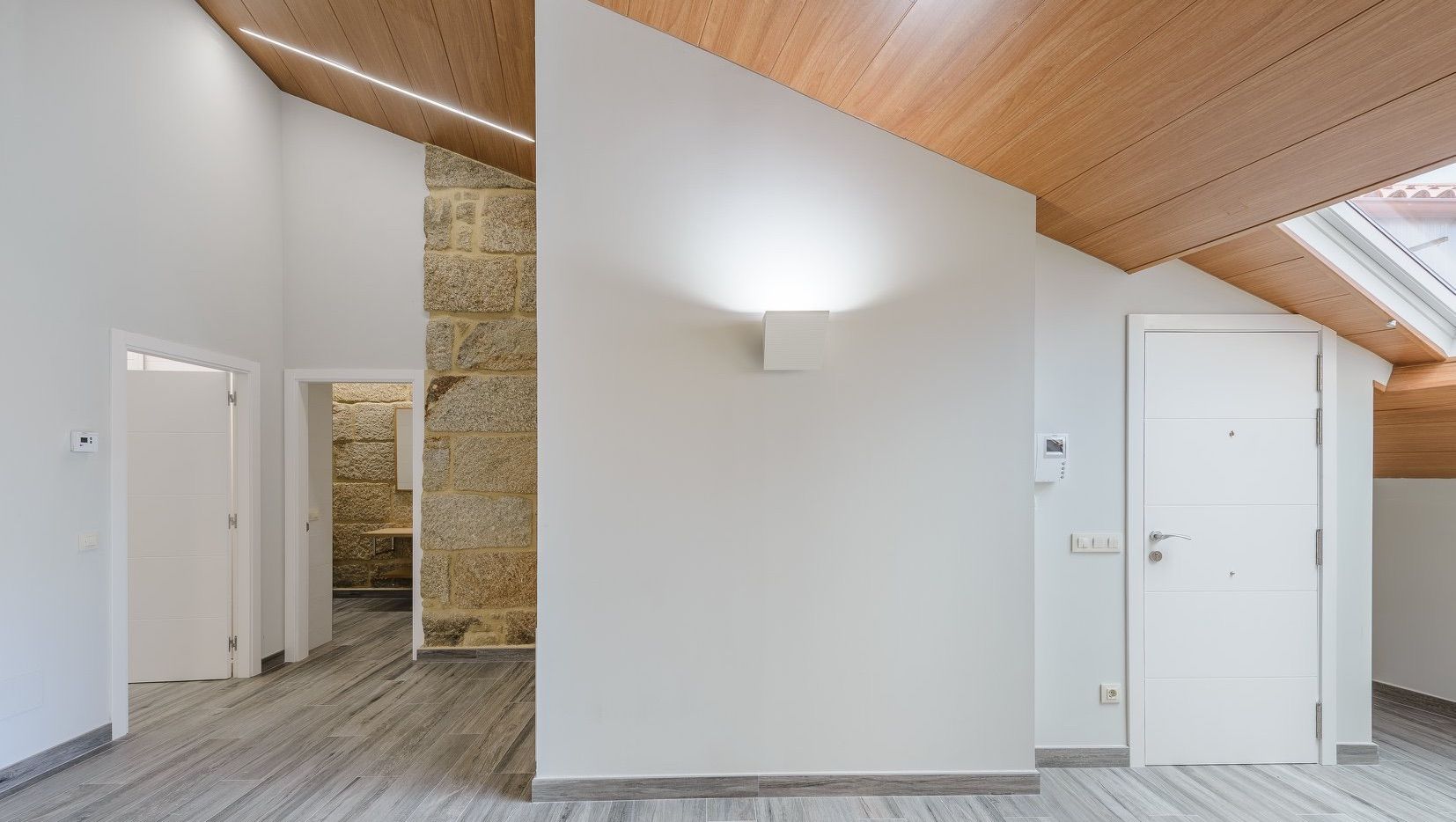 Una habitación vacía con paredes blancas y techo de madera.