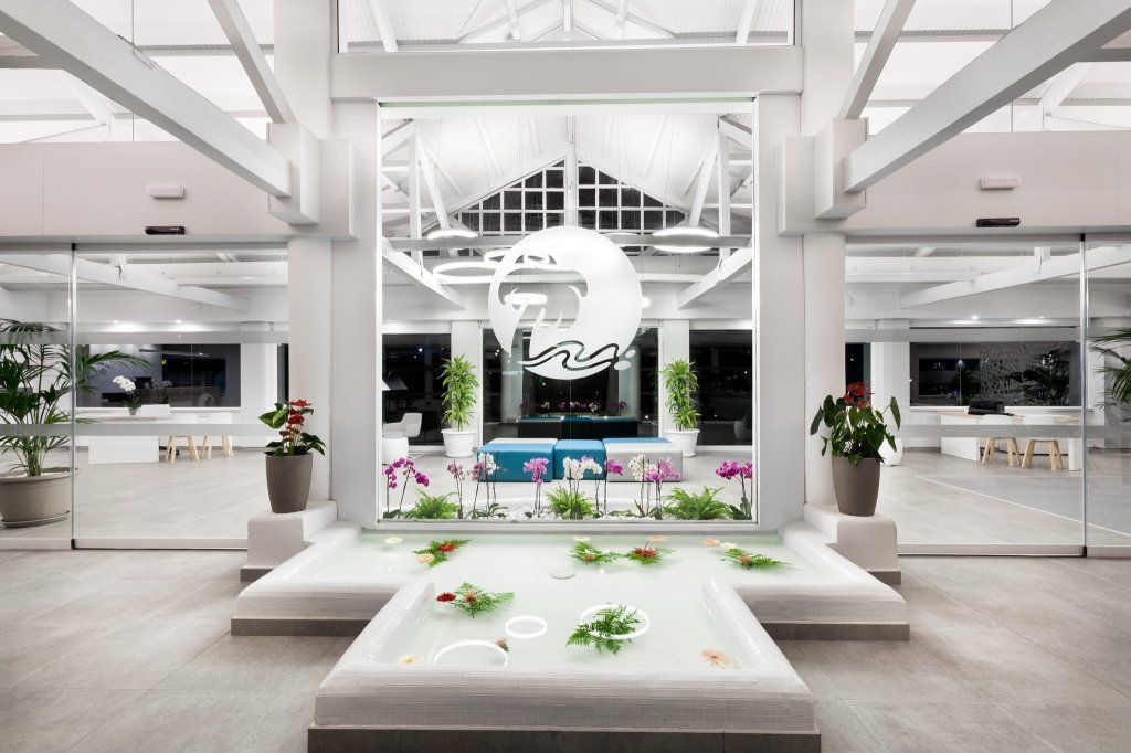 Una gran habitación blanca con una gran ventana y un estanque en el medio.