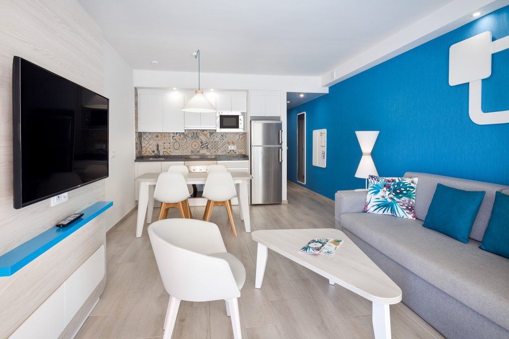 Una sala de estar con sofá, sillas, mesa y televisión.