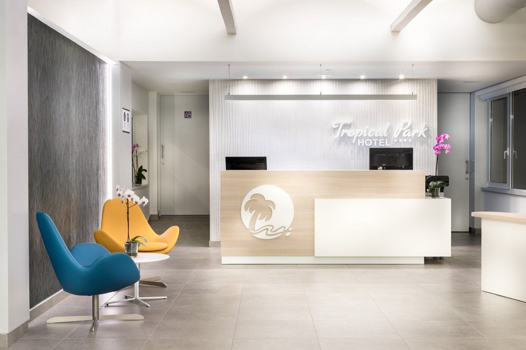 Un vestíbulo con una silla azul y una silla amarilla frente a un mostrador de recepción.