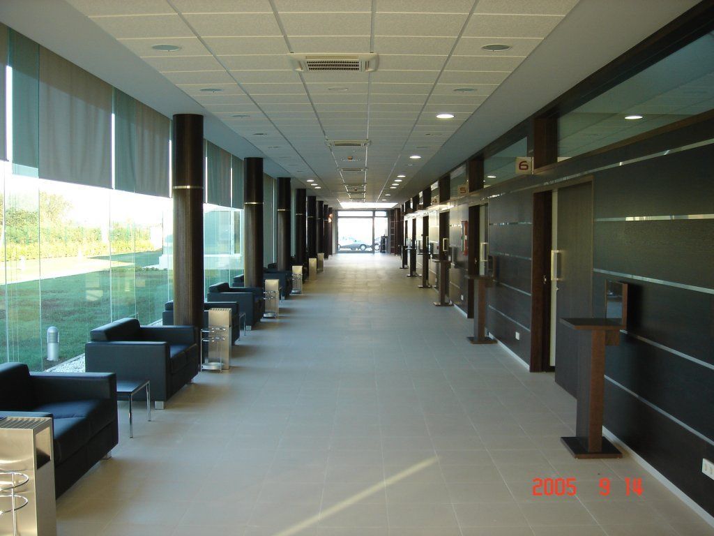 Un largo pasillo con muchas ventanas y sillas.