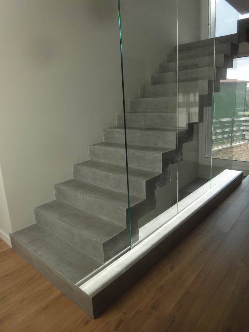 Una escalera con barandilla de cristal y suelo de madera.