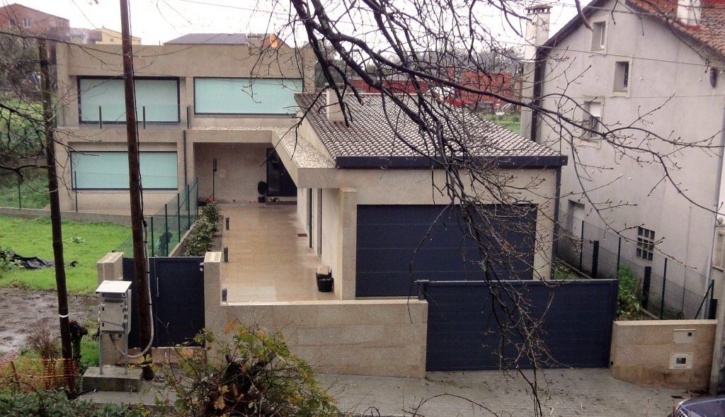 Una casa con una puerta de garaje negra está rodeada de árboles.